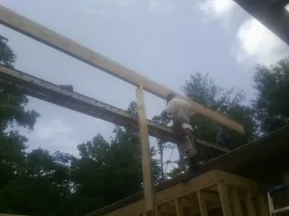 Carpenter setting a ridge beam over a new addition frame — Ice Dam Removal by Roofing Brothers in Butte City