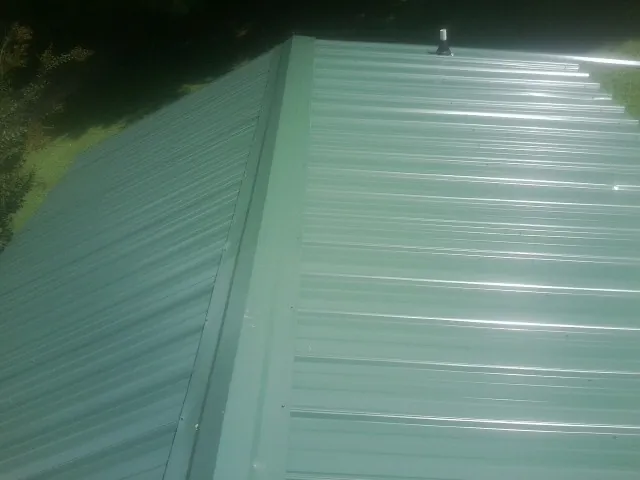 New green metal panels meeting at the ridge of a roof — Flat Roof Repair work by our crew in Butte City