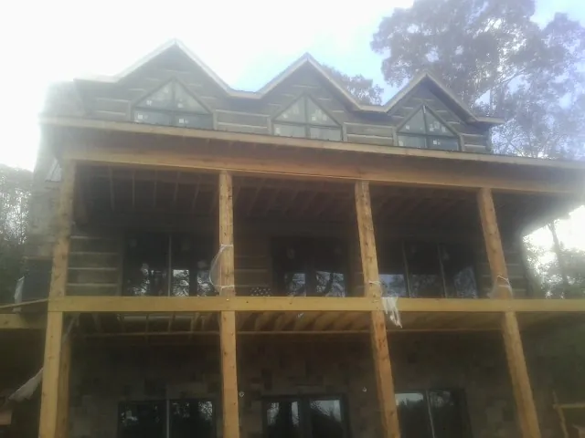 Dormers and porch framing on a large log home under construction — Roof Coating work by our crew in Butte City