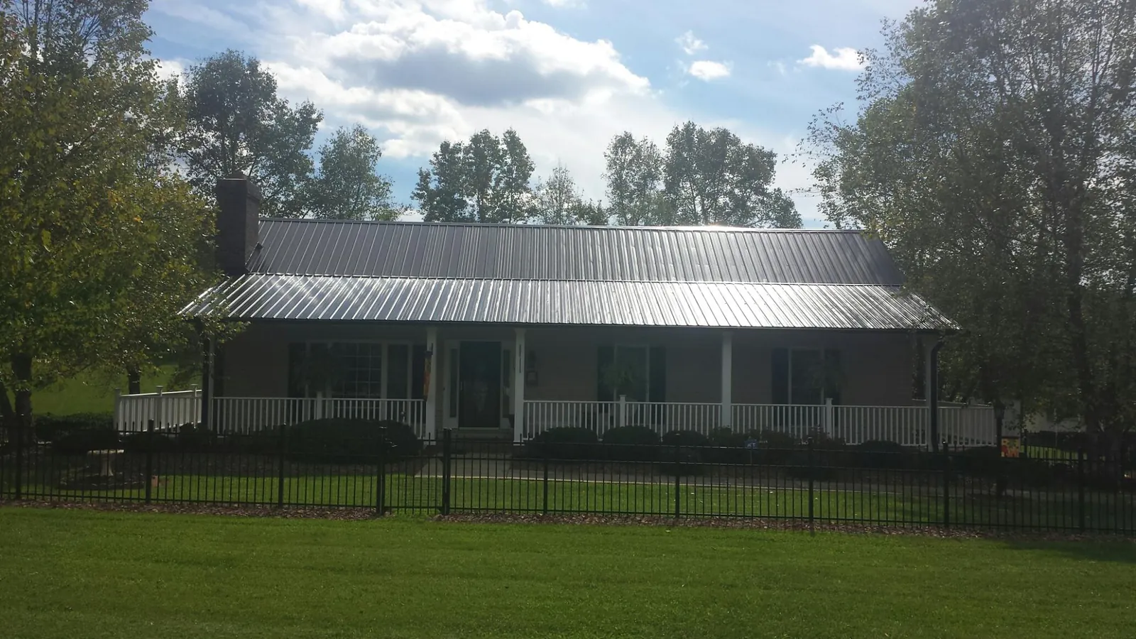 Gray metal roof on a brick ranch with a full width front porch — Gutter Guard Installation work by our crew in Butte City