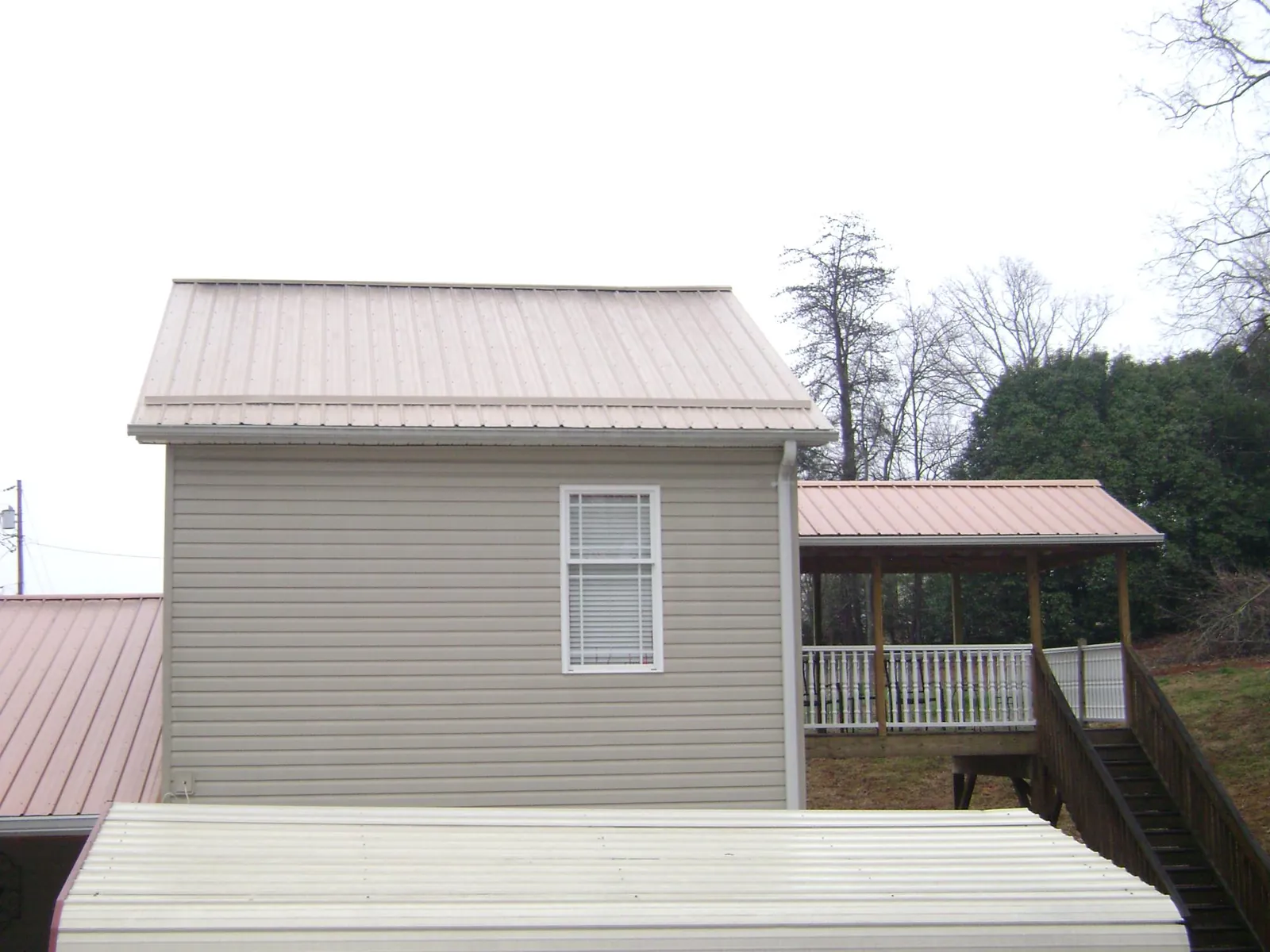 Tan metal roofs on a two story addition and attached porch, from a Roof Replacement job in Butte City