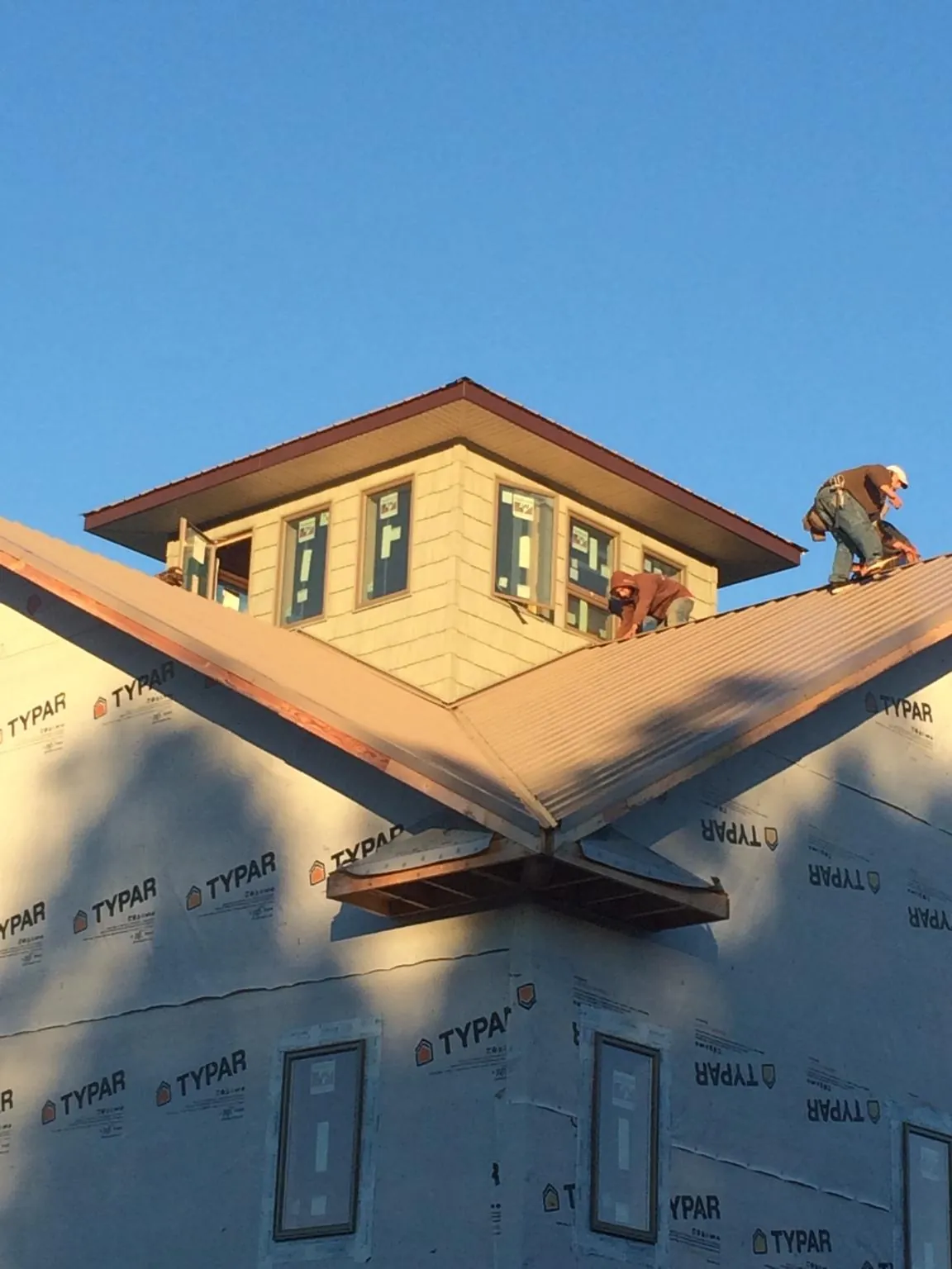Roofers working around a rooftop cupola on a new metal roof at sunset — Roof Waterproofing in Butte City by Roofing Brothers